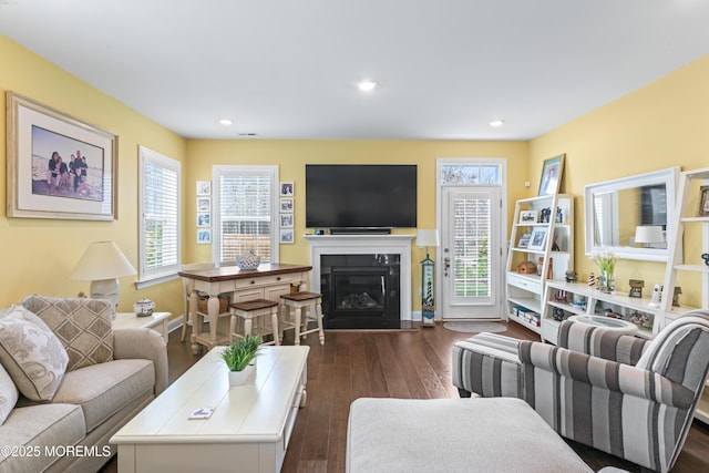 living room featuring visible vents, dark wood-style floors, a glass covered fireplace, and recessed lighting