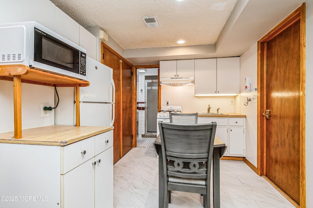 438 Carlisa Dr, Brick, NJ 08723 - kitchen featuring white appliances, under cabinet range hood, light marble finish flooring, white cabinets, and a textured ceiling