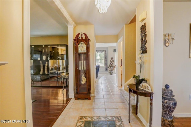 corridor with light tile patterned flooring, ornate columns, and baseboards
