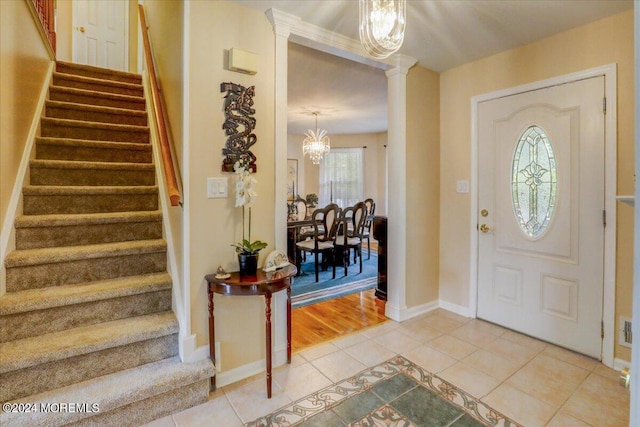 foyer featuring stairway, an inviting chandelier, light tile patterned floors, baseboards, and ornate columns