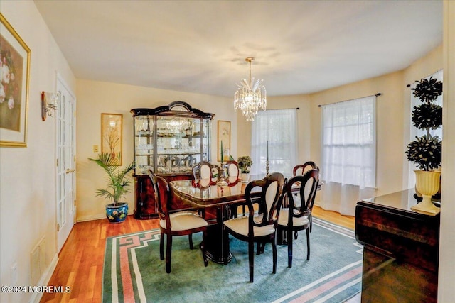 dining space featuring baseboards, visible vents, wood finished floors, and a chandelier