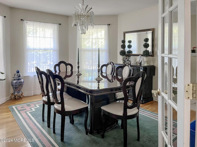 dining area featuring a healthy amount of sunlight, a chandelier, and wood finished floors