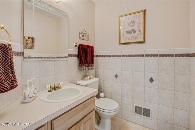 bathroom with tile patterned flooring, vanity, tile walls, toilet, and visible vents