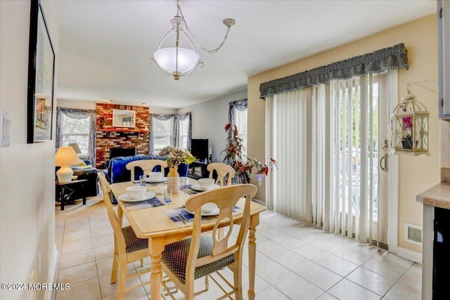 dining space with light tile patterned floors, a brick fireplace, and visible vents