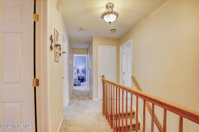 hallway with light carpet, baseboards, and an upstairs landing