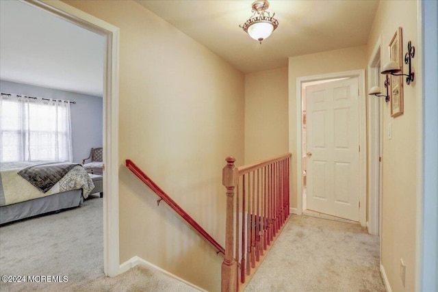 corridor with baseboards, an upstairs landing, and carpet floors