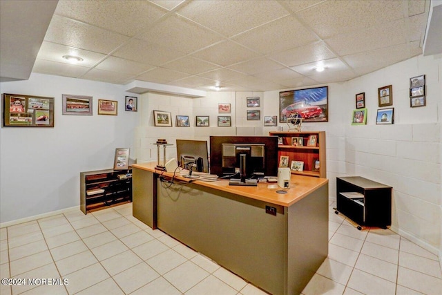 office space featuring concrete block wall, light tile patterned floors, and a paneled ceiling