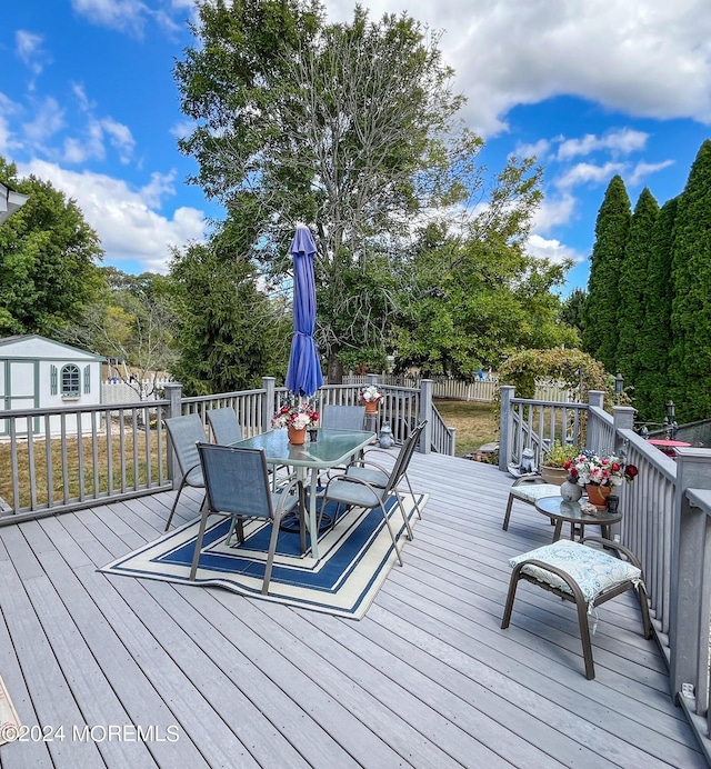 wooden deck featuring outdoor dining area and an outdoor structure