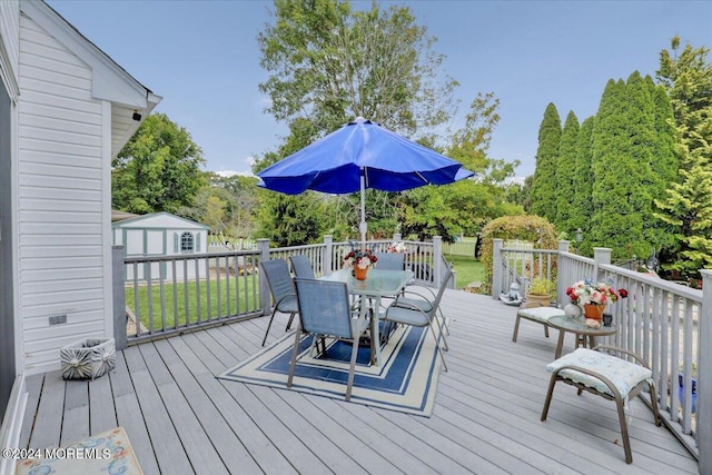 wooden deck with outdoor dining space and a yard