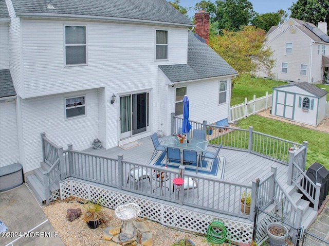 back of house featuring an outdoor structure, roof with shingles, a lawn, fence private yard, and a storage shed