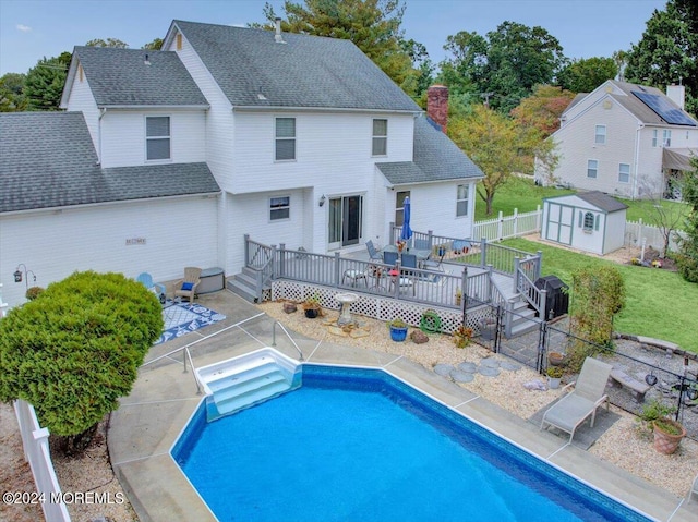 back of property with an outbuilding, a deck, a storage shed, fence private yard, and a lawn