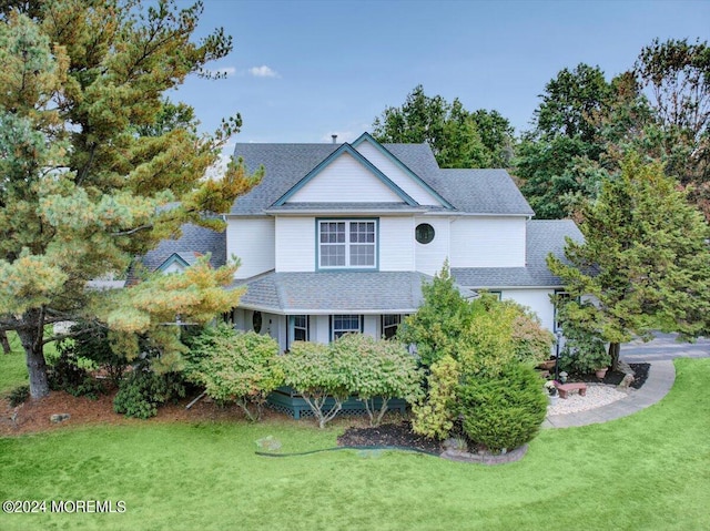 traditional home featuring a front lawn and roof with shingles