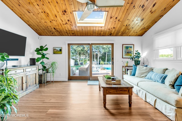 living area with lofted ceiling, a skylight, light wood-type flooring, baseboards, and wood ceiling