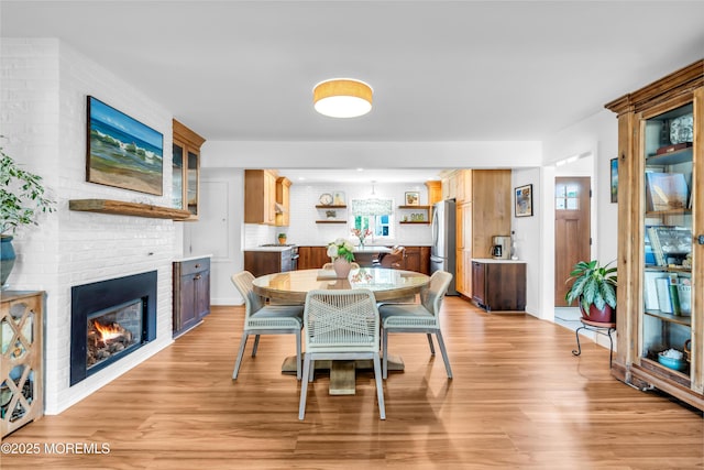 dining room with a brick fireplace, light wood finished floors, and plenty of natural light