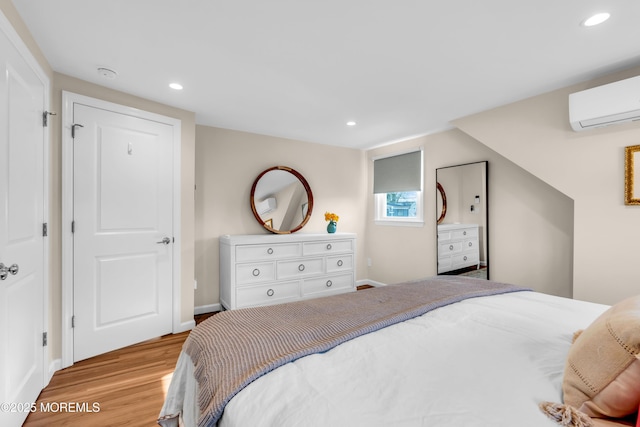 bedroom with a wall mounted air conditioner, light wood-type flooring, baseboards, and recessed lighting