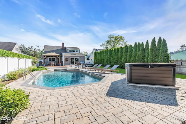 view of pool featuring a hot tub, a patio, a fenced backyard, an exterior structure, and an outdoor structure