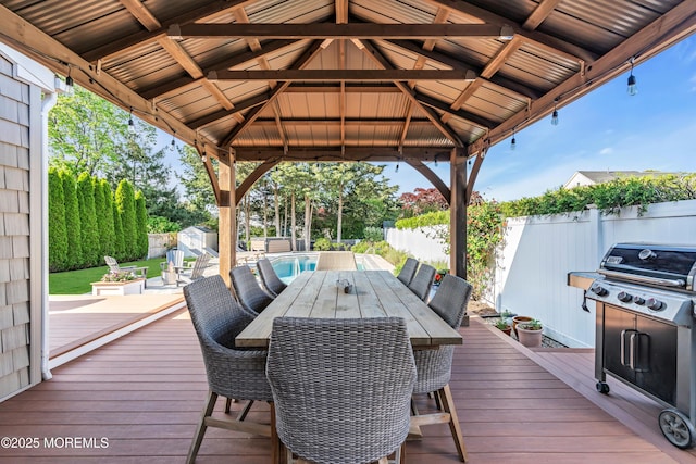 deck featuring a gazebo, a fenced backyard, outdoor dining area, a shed, and area for grilling