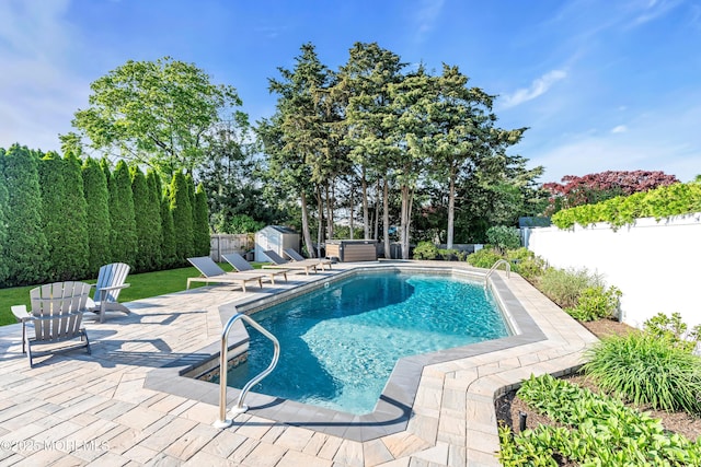 view of swimming pool featuring a shed, a patio area, a fenced backyard, and an outbuilding