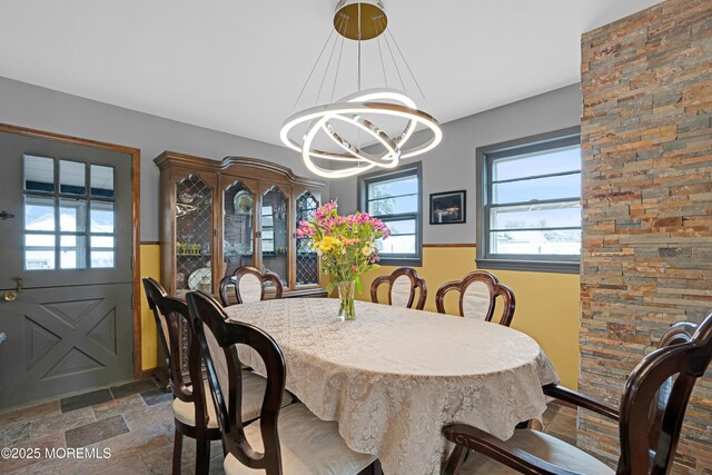 dining space with a notable chandelier and stone tile flooring