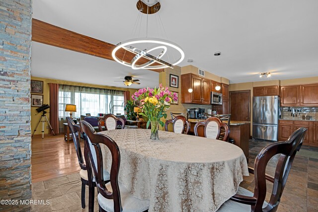 dining area featuring visible vents, ceiling fan with notable chandelier, and stone finish flooring