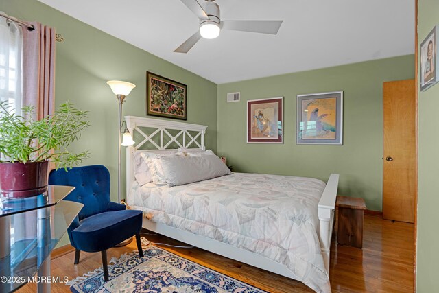 bedroom with a ceiling fan, wood finished floors, and visible vents