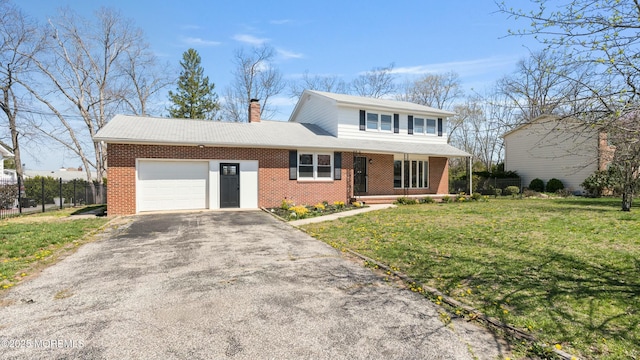 view of front of house featuring a chimney, aphalt driveway, a front lawn, brick siding, and a garage
