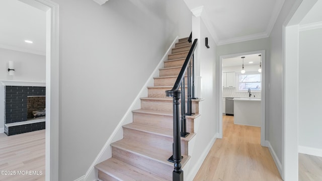 stairs with baseboards, crown molding, wood finished floors, and a fireplace