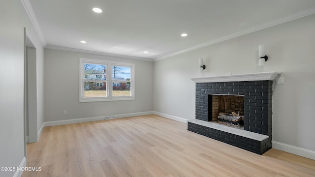 unfurnished living room with light wood-style floors, a brick fireplace, and crown molding