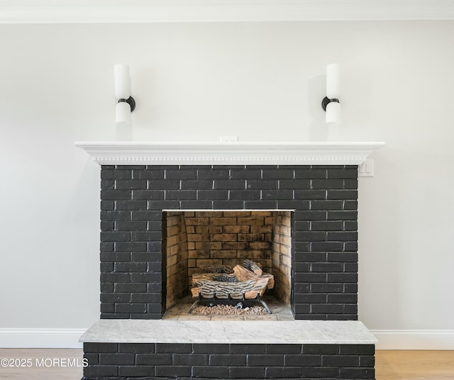 interior details with baseboards, crown molding, wood finished floors, and a fireplace