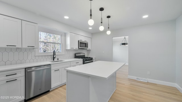 kitchen with tasteful backsplash, a sink, light countertops, appliances with stainless steel finishes, and visible vents
