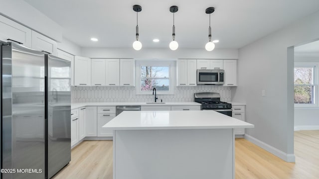 kitchen featuring decorative backsplash, stainless steel appliances, light wood-type flooring, and a sink