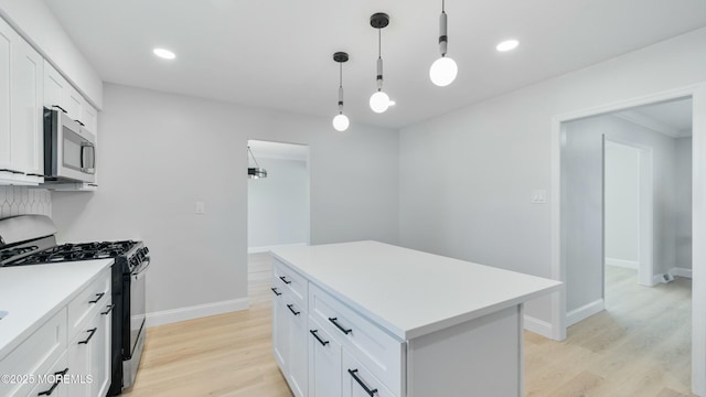 kitchen featuring light wood-style floors, stainless steel appliances, light countertops, white cabinetry, and a kitchen island