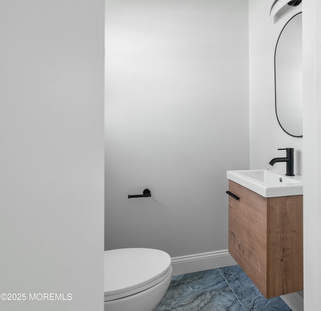 bathroom featuring baseboards, toilet, and vanity