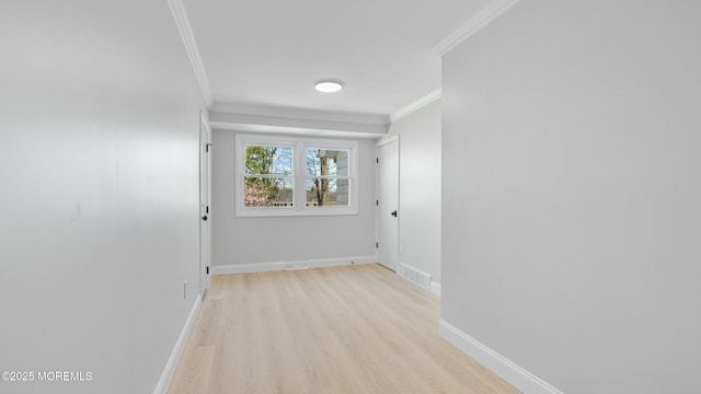 hallway with light wood-style floors, visible vents, crown molding, and baseboards