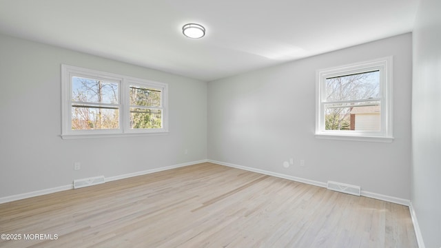 unfurnished room with light wood finished floors, baseboards, and visible vents