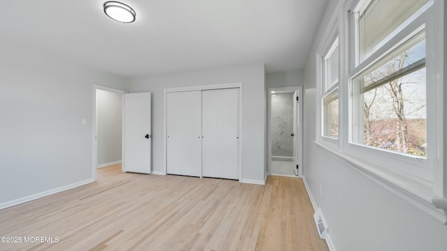 unfurnished bedroom with light wood-style flooring, visible vents, baseboards, a closet, and connected bathroom