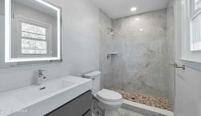 full bath with a tile shower, toilet, vanity, and recessed lighting