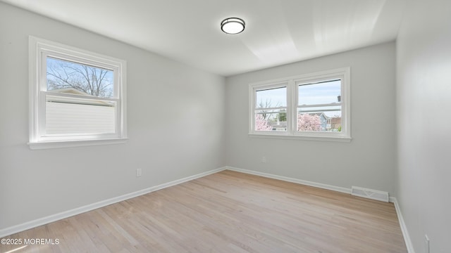empty room featuring baseboards, wood finished floors, and visible vents