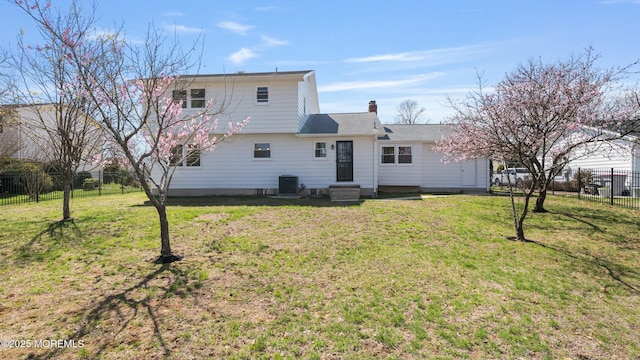 rear view of property featuring fence, a lawn, a chimney, and central AC unit