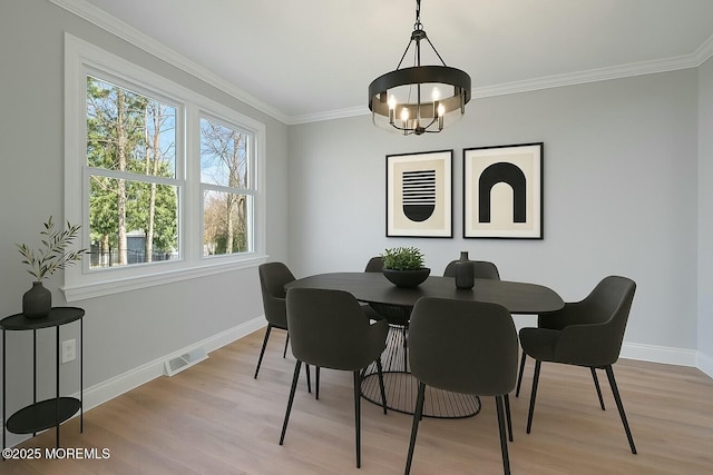 dining room with baseboards, ornamental molding, light wood finished floors, and an inviting chandelier