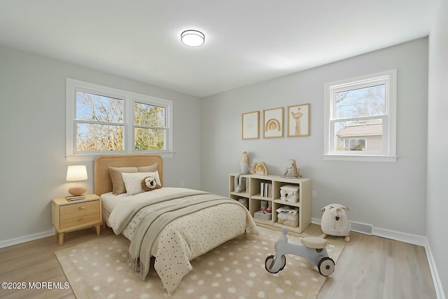 bedroom featuring baseboards, wood finished floors, and multiple windows