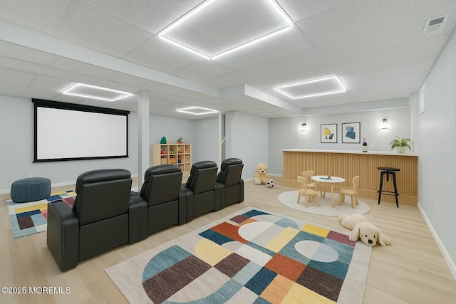 cinema featuring visible vents, a paneled ceiling, wood finished floors, and a bar