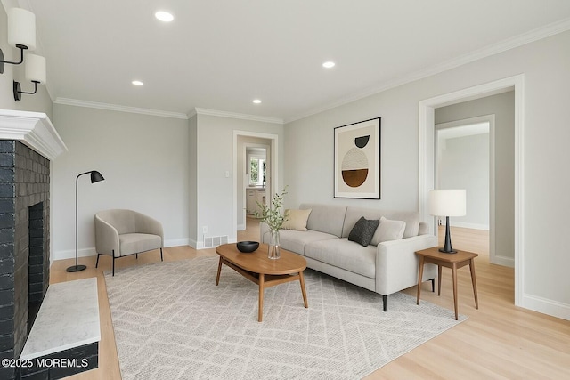 living area featuring light wood finished floors, baseboards, recessed lighting, crown molding, and a fireplace