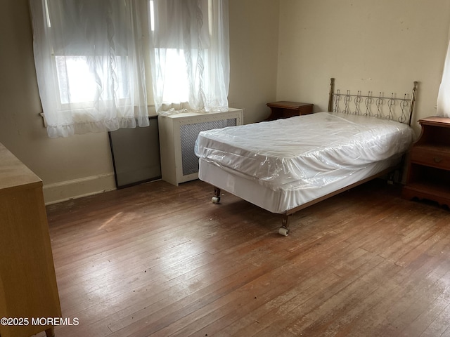 bedroom featuring radiator heating unit and hardwood / wood-style flooring