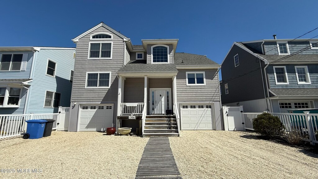 view of front of home with roof with shingles, driveway, a garage, and fence