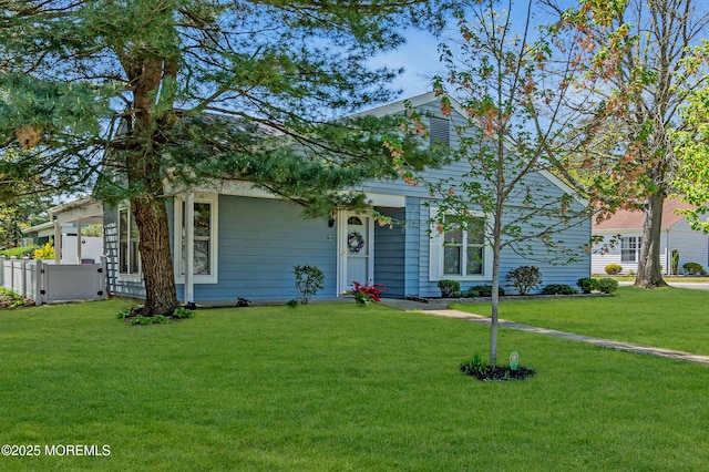 view of property hidden behind natural elements featuring fence and a front yard