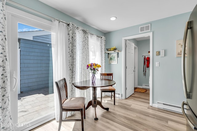 dining area featuring visible vents, light wood-style floors, baseboards, a baseboard heating unit, and a baseboard radiator