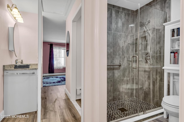 bathroom featuring toilet, baseboards, a shower stall, and wood finished floors
