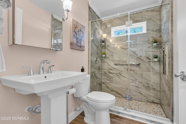bathroom with toilet, a marble finish shower, and wood finished floors