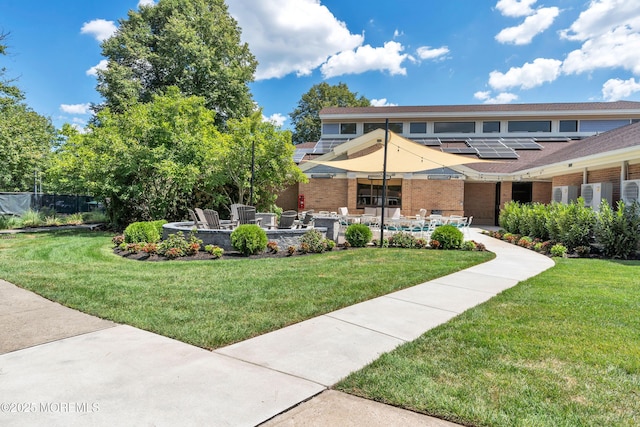 view of front of property with a front yard, roof mounted solar panels, and a patio area